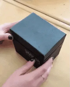 A six-panel image sequence shows hands opening a black jewelry box to reveal a gold ring, then placing the ring back in the…