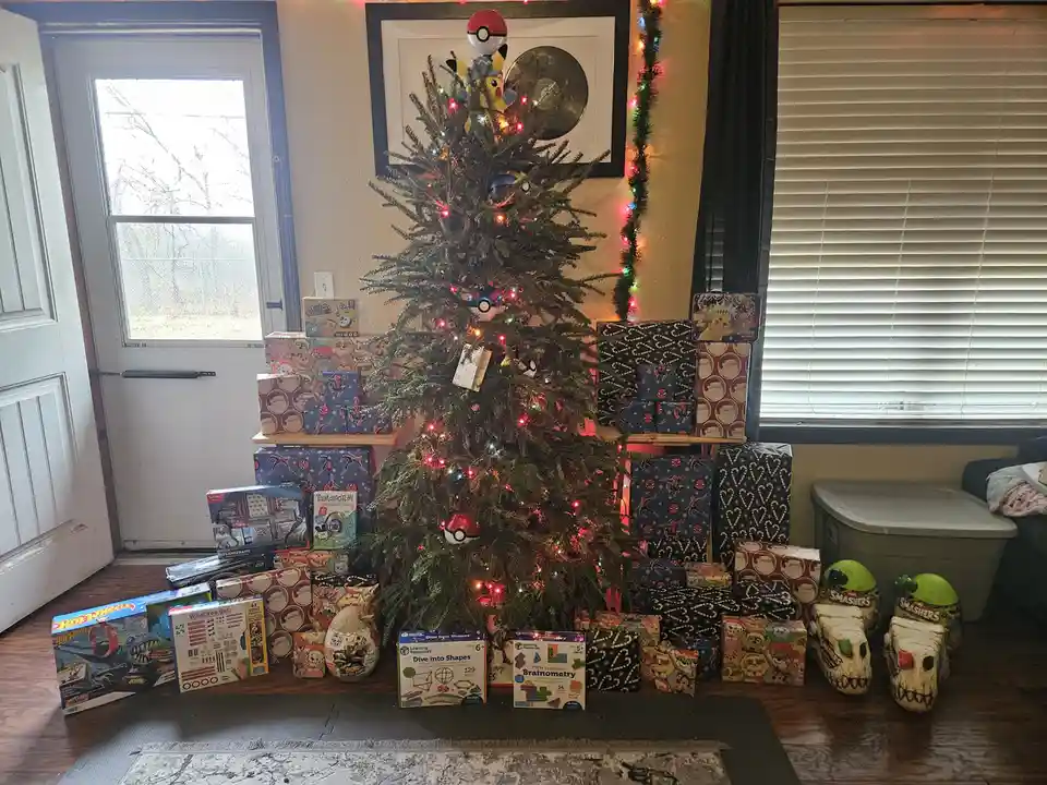 A Christmas tree is heavily decorated with Pokémon-themed ornaments and surrounded by dozens of wrapped gifts, including Hot…