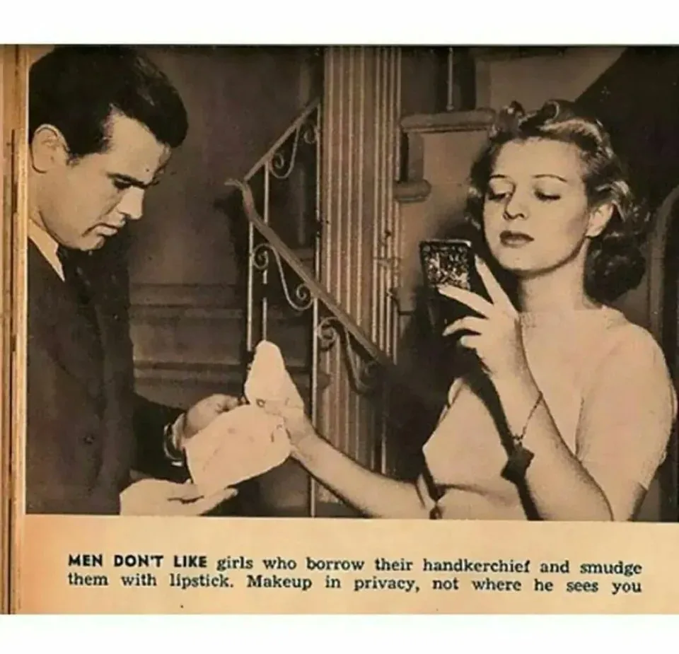 A vintage black-and-white photo shows a man in a suit looking down at a handkerchief being handed to him by a woman in a…