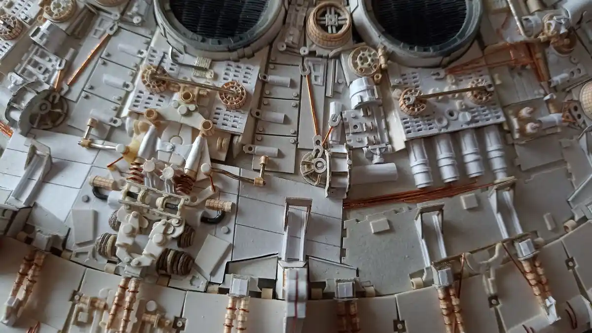 A close-up of a highly detailed, white and copper-colored model of a complex mechanical or electrical system, possibly a…