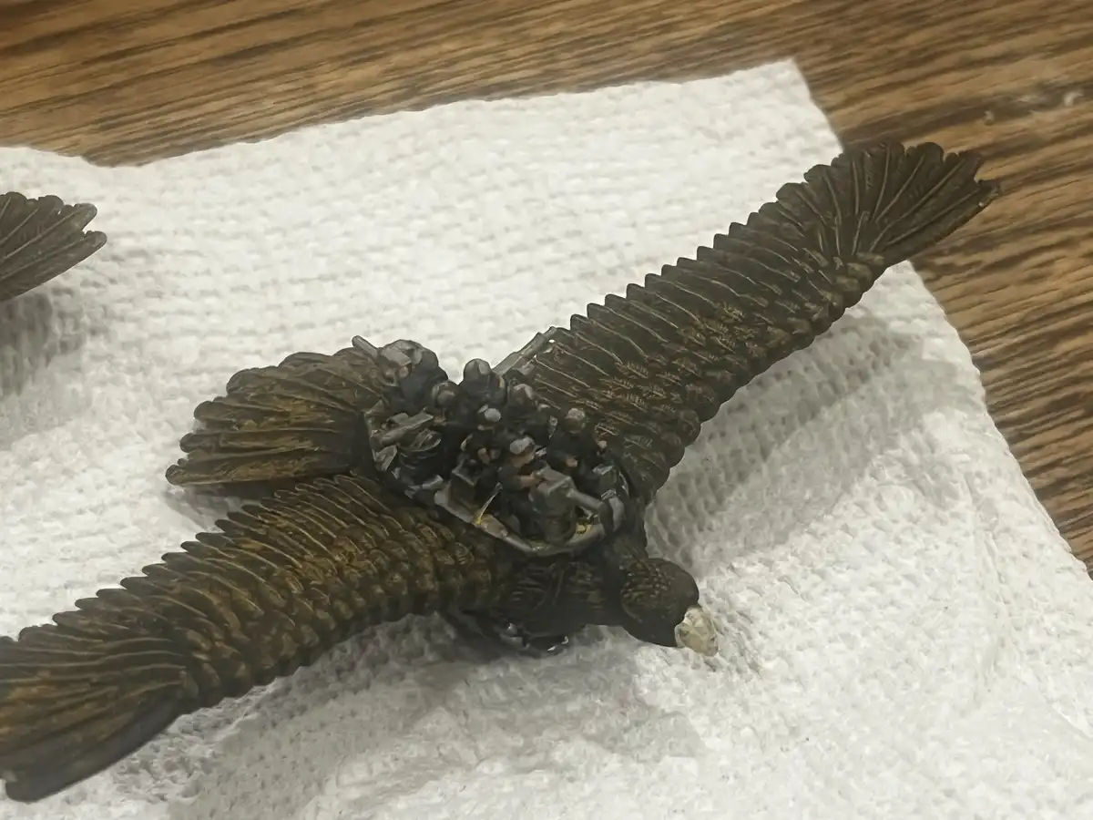 A detailed miniature model of a large bird, likely a vulture or eagle, with its wings spread wide, is resting on a white…
