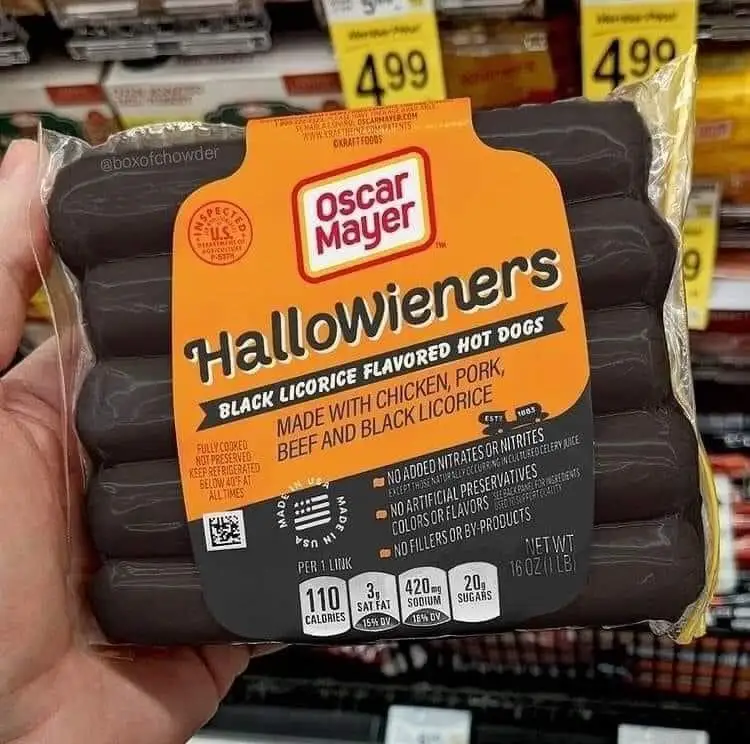 A hand holds a package of Oscar Mayer 'Hallowieners' hot dogs, which are black licorice flavored and made with chicken…