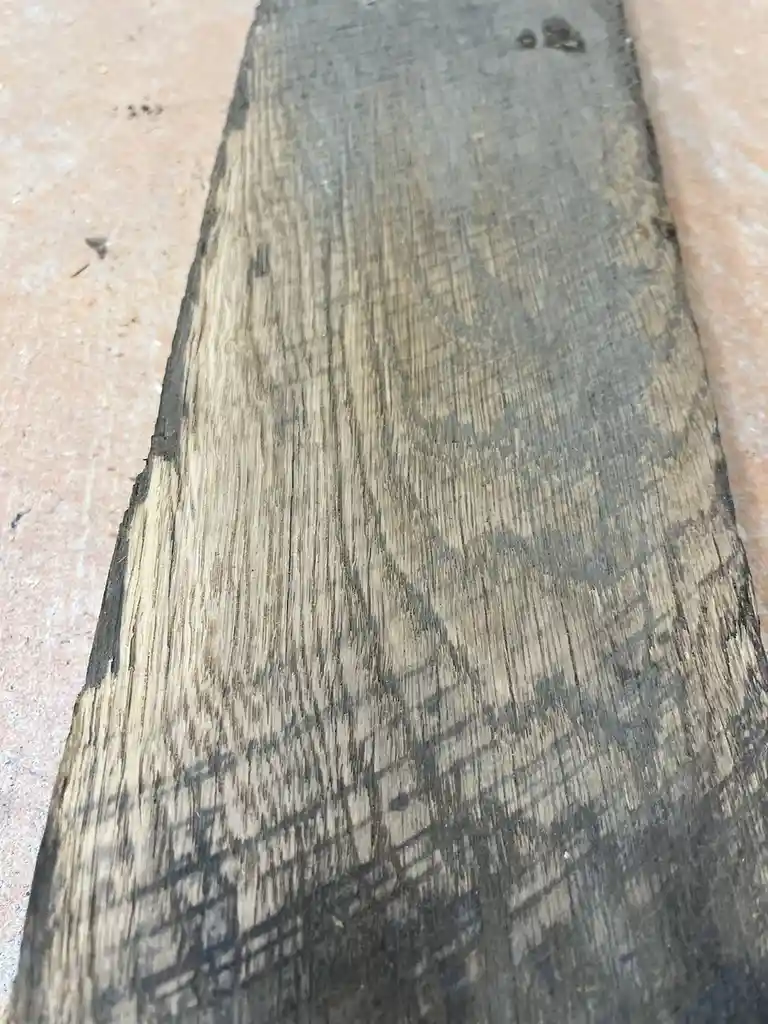 A close-up photo of a weathered wooden plank with visible grain patterns that resemble a human face, set against a…