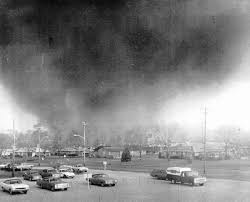 A black-and-white photo shows a large, ominous tornado approaching a parking lot filled with vintage cars. The overlaid text…