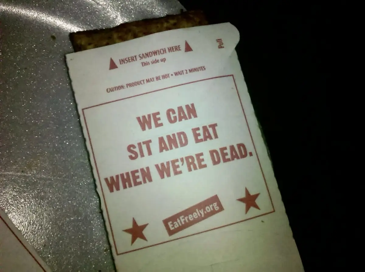 A close-up of a white sandwich bag with red text, showing instructions like 'INSERT SANDWICH HERE' and 'CAUTION: PRODUCT MAY…