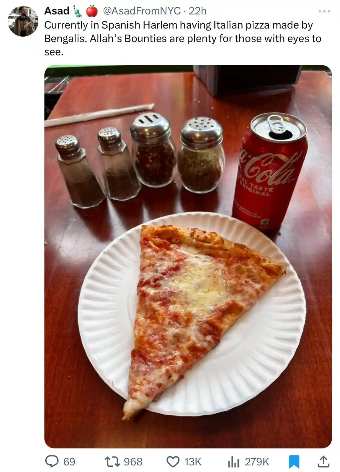 A single slice of cheese pizza on a white paper plate sits on a wooden table next to a red can of Coca-Cola and four glass…