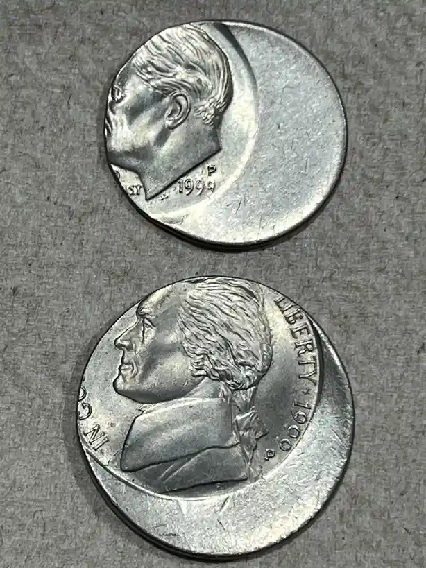 Two 1999 U.S. coins are shown side-by-side: a silver-colored Kennedy half-dollar with John F. Kennedy's profile and a…