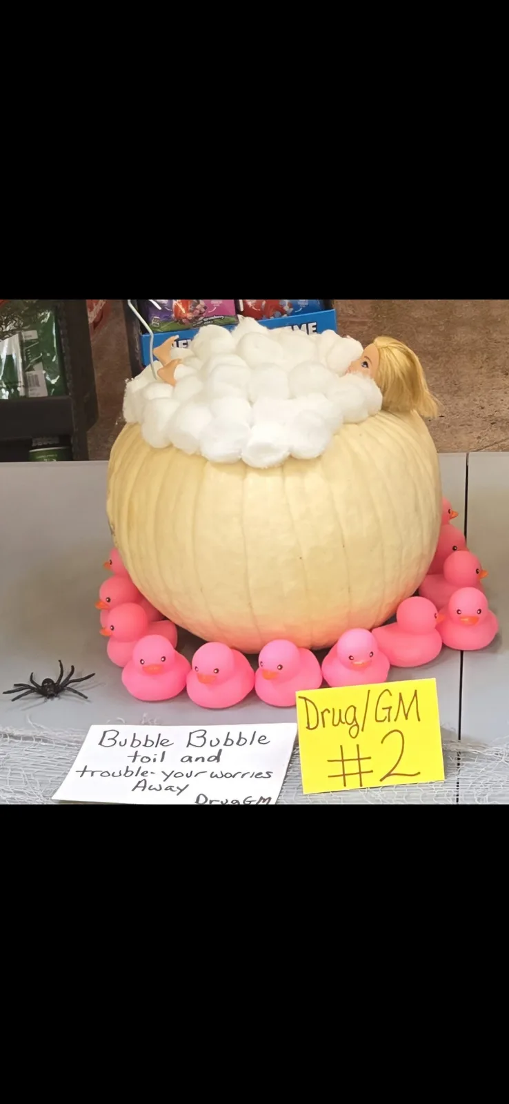 A pale yellow pumpkin is carved to resemble a bathtub, filled with white cotton balls to look like bubbles, and contains a…