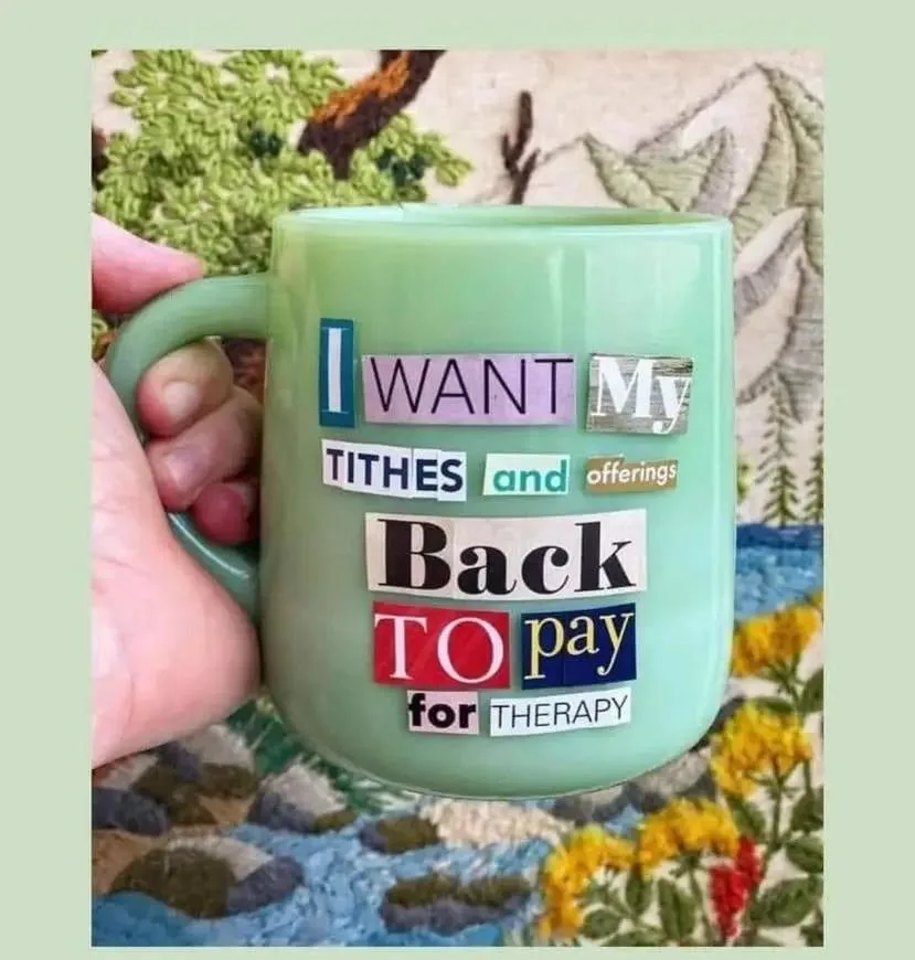 A light green ceramic mug is held by a person's hand, featuring a collage of cut-out letters and words in various fonts and…