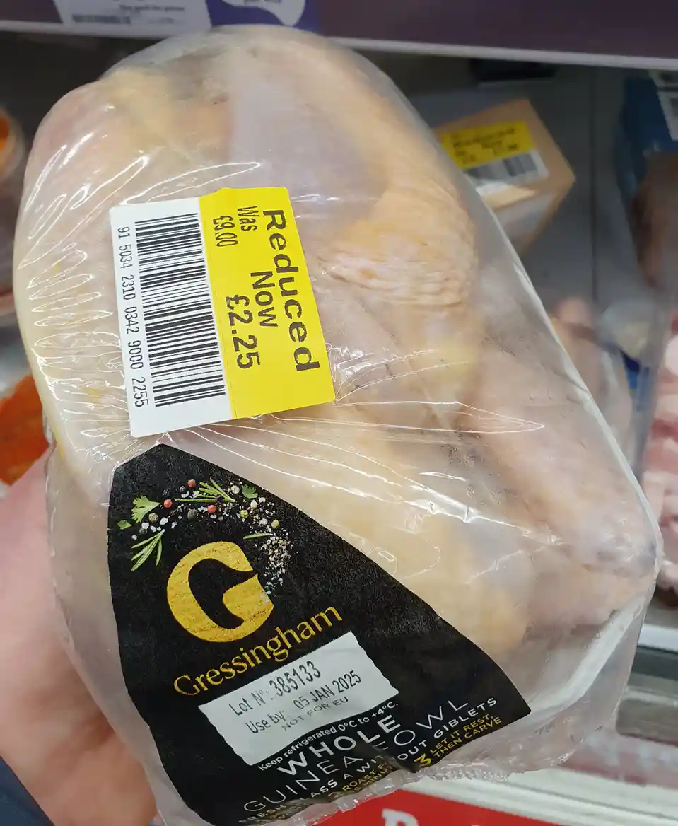 A person holds a whole guinea fowl in clear plastic packaging with a black label reading 'Gressingham WHOLE GIBLET' and a…