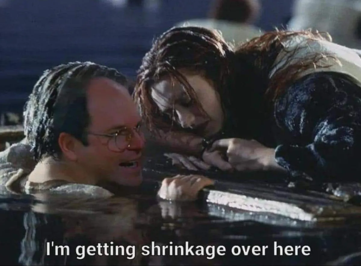 A man and woman are partially submerged in water, looking at each other with expressions of distress or concern. The man…