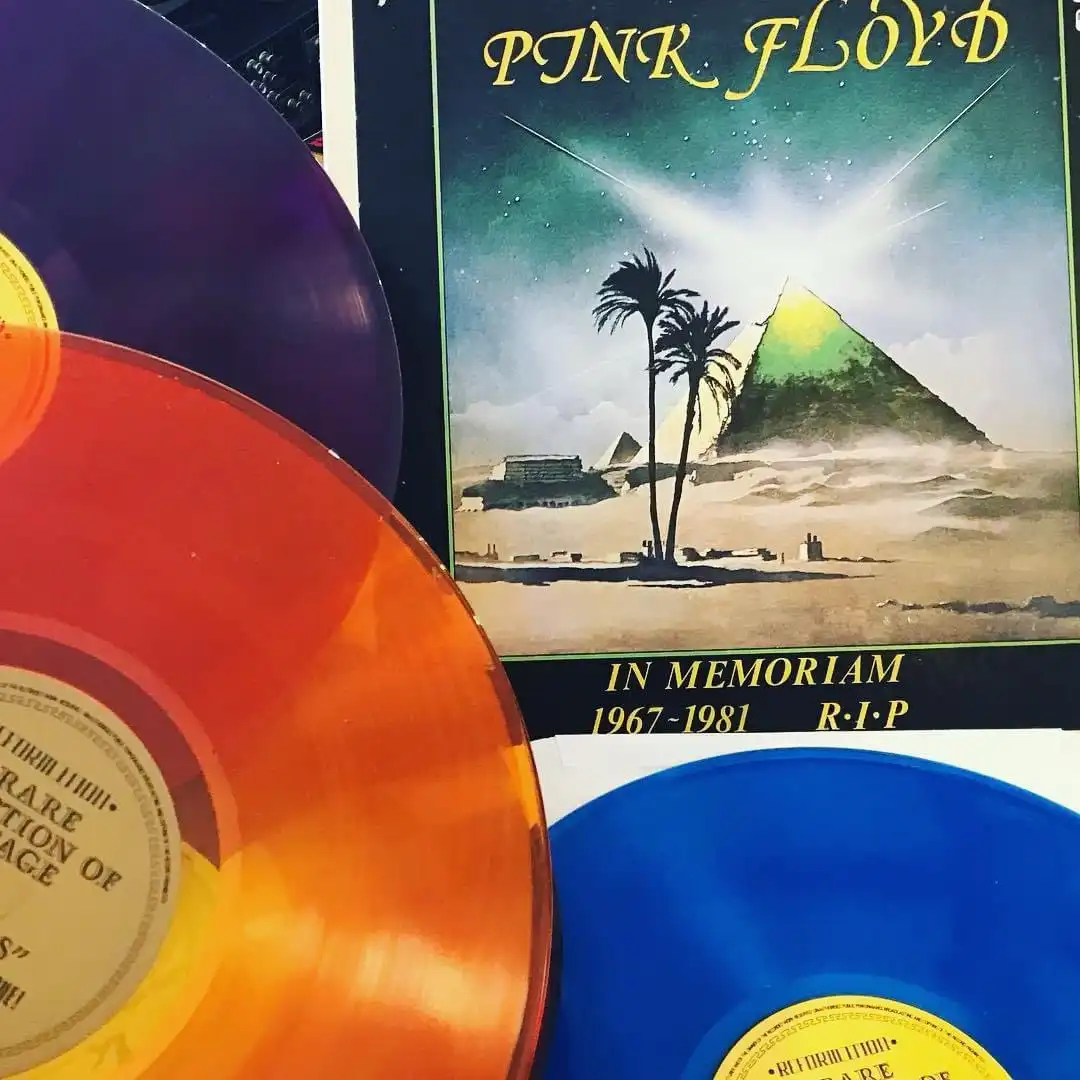 A close-up photo shows three colorful vinyl records — purple, orange, and blue — partially obscuring the album cover of Pink…