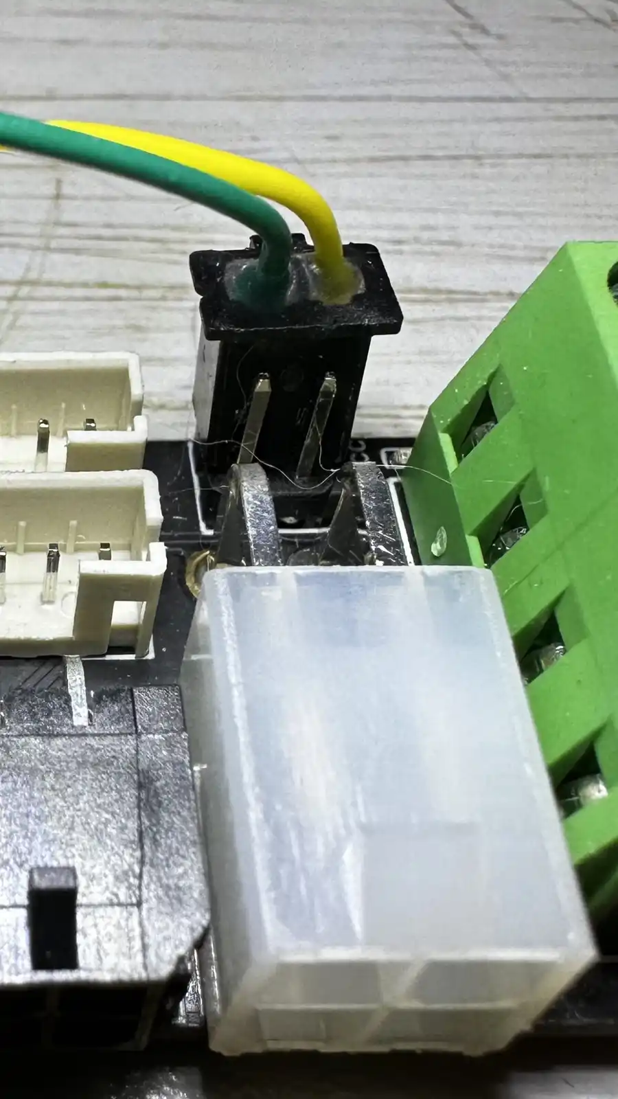 A close-up photo of an electronic circuit board with various connectors, including a black terminal block with green and…