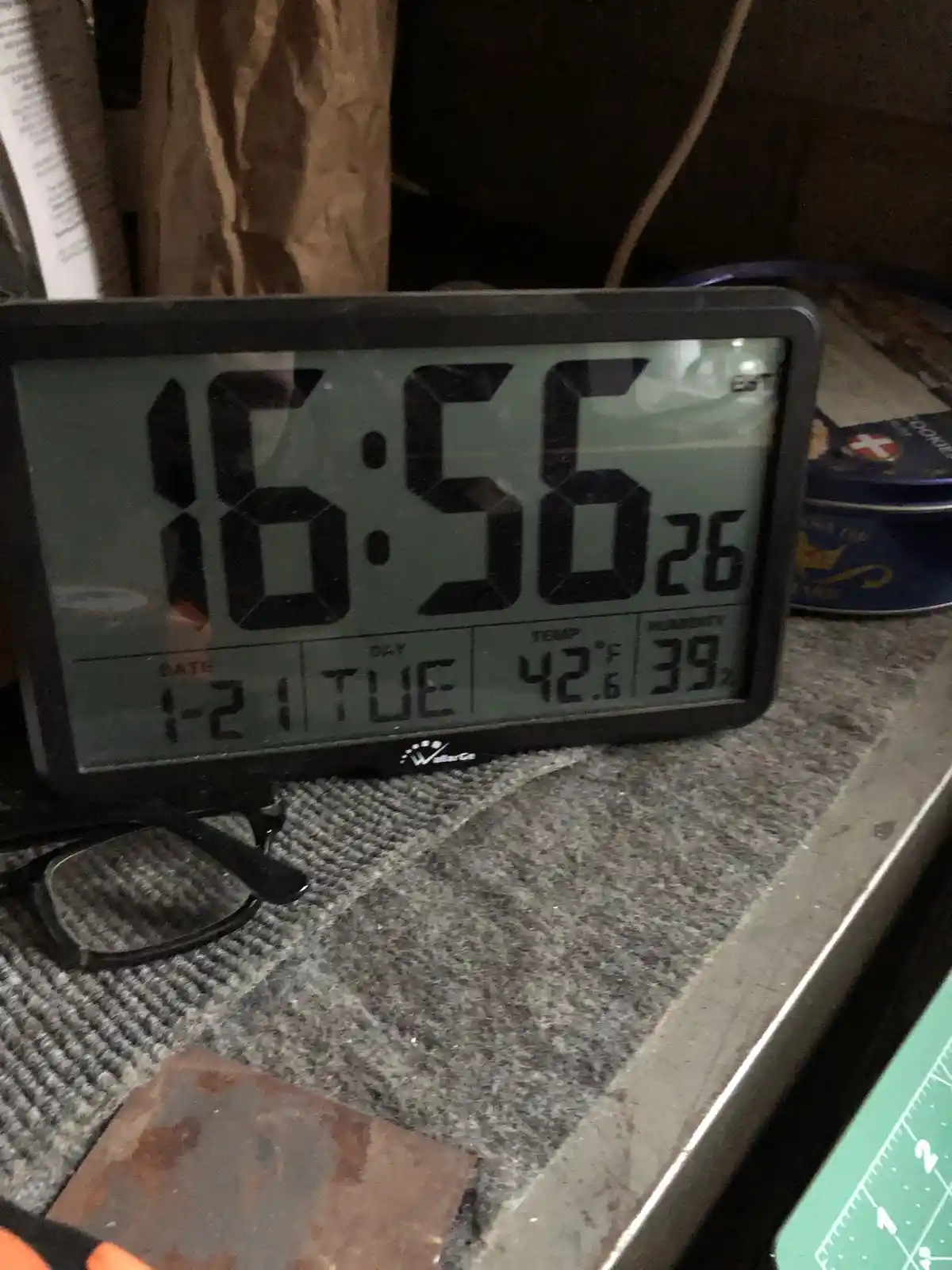 A digital clock displays the time 16:56 and date 1-21 TUE, with temperature 42.6°F and humidity 39%. The clock sits on a…