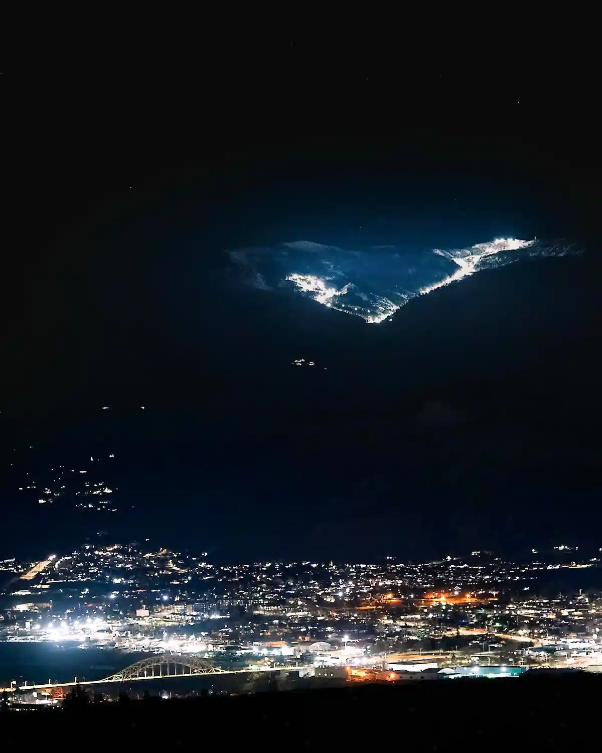 A nighttime photo shows a brightly lit ski resort on a mountain above a cityscape with a bridge, overlaid with the text 'i'm…