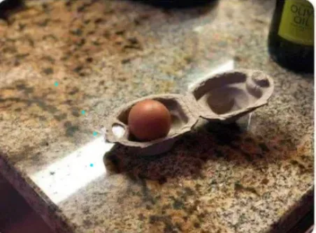 A single brown egg sits in one half of a cardboard egg carton on a speckled granite countertop, with the other half empty…