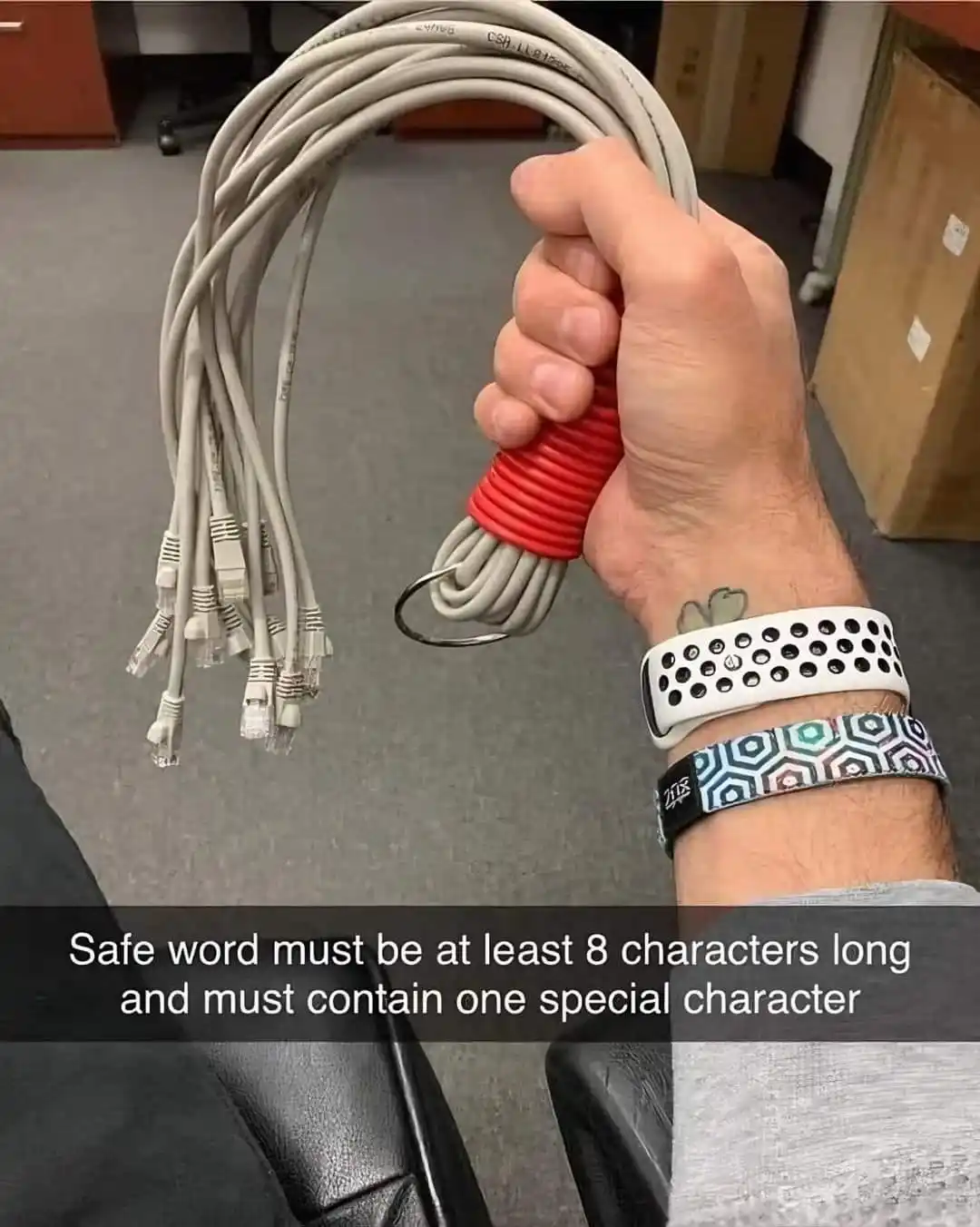 A person's hand grips a bundle of Ethernet cables, which are wrapped with a red band and attached to a keychain. The hand…