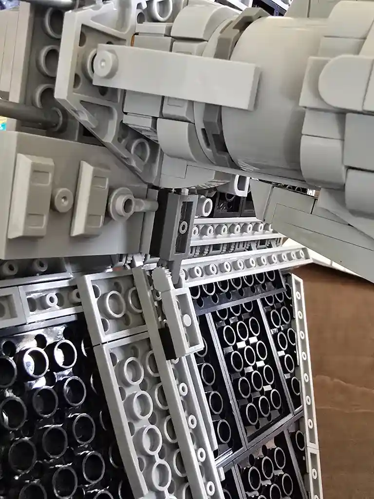 A close-up photo of a large, intricate grey Lego model, showing detailed mechanical parts and stud patterns. The overlaid…