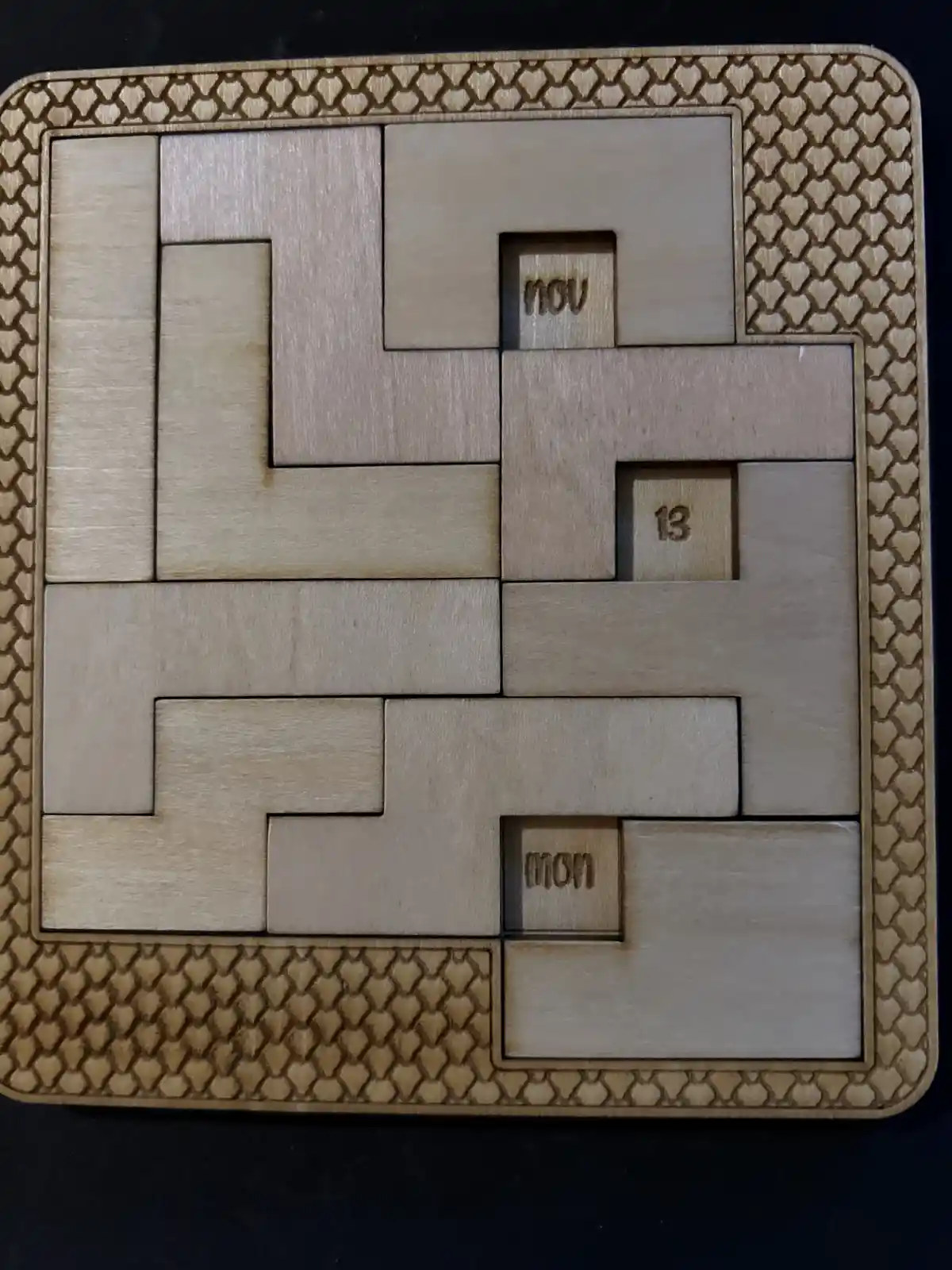 A wooden puzzle calendar with interlocking pieces, three small squares show the text 'nov', the number '13', and 'mon'…