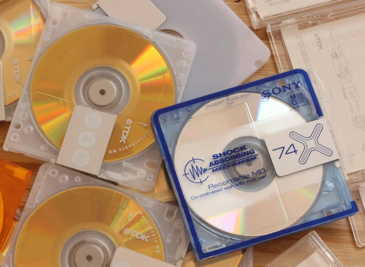 A close-up photo shows several MiniDiscs in their plastic cases, including a blue Sony disc labeled 'SHOCK ABSORBING…