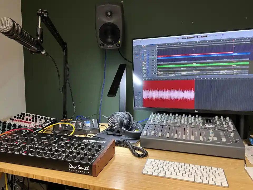 A professional music production setup with a computer monitor displaying a digital audio workstation with audio tracks and a…