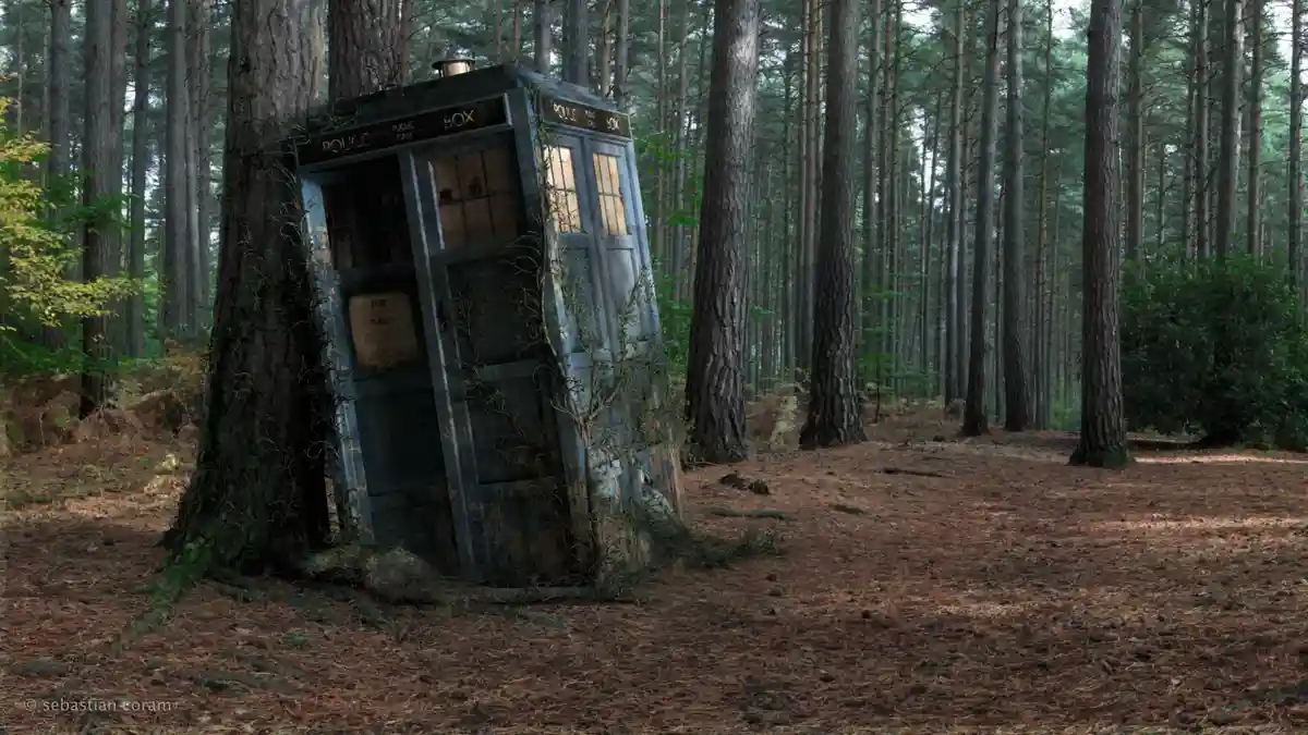 A weathered, blue police public call box from the TV show Doctor Who is shown leaning precariously against a large tree in a…