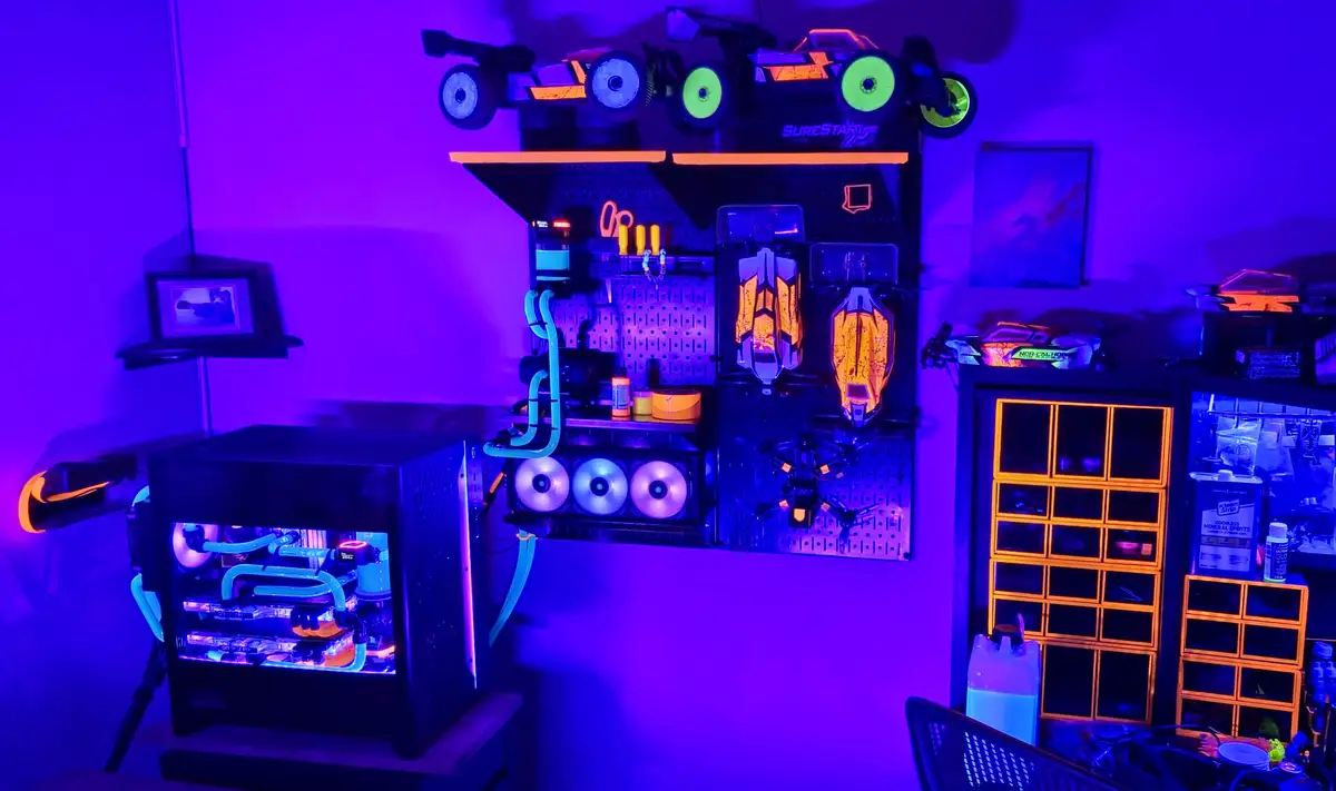 A room bathed in purple light features a custom-built PC with glowing blue liquid cooling tubes and RGB fans, mounted next…