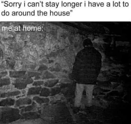 A black-and-white photo shows a person from behind, standing in a dimly lit, rough stone-walled room, possibly a basement or…