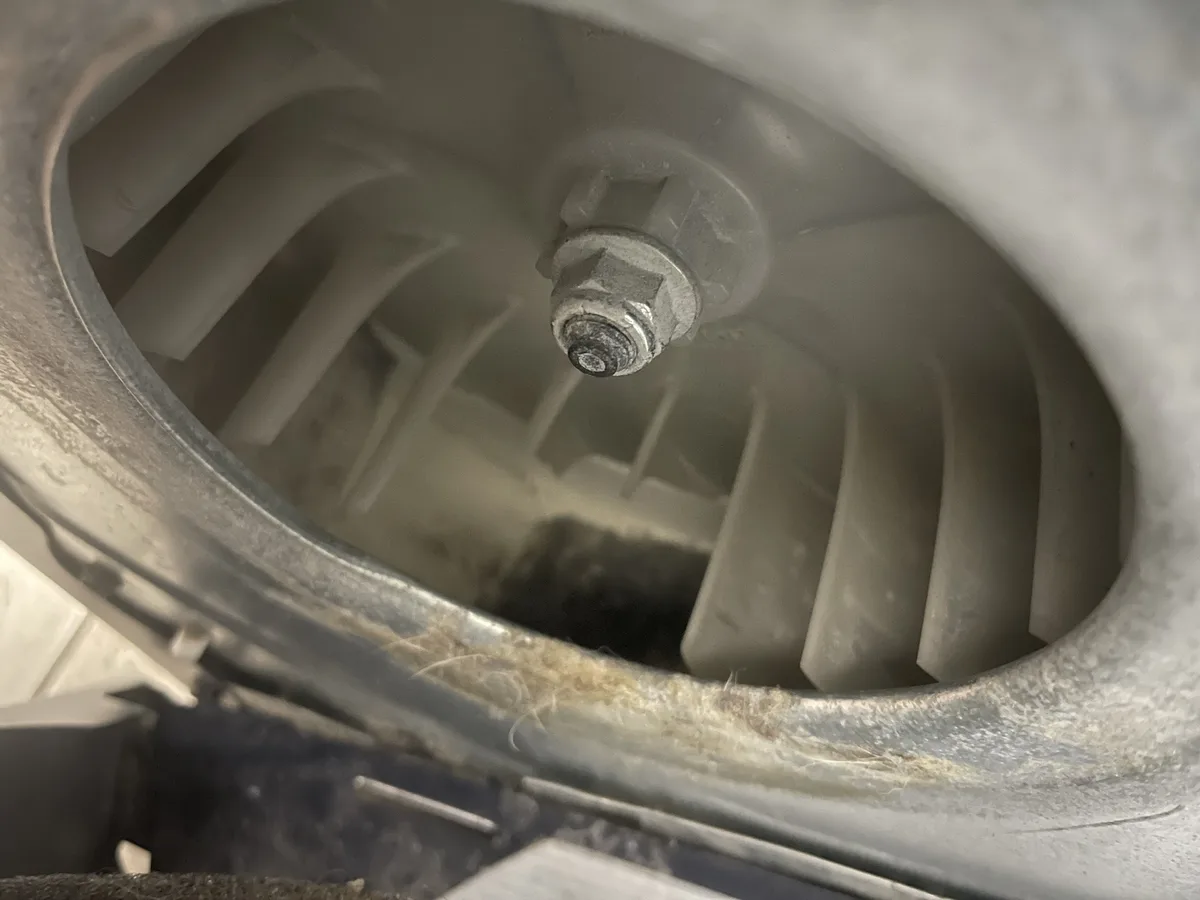 A close-up photo shows the inside of a washing machine drum, revealing a central bolt and dirty, grimy interior with lint…