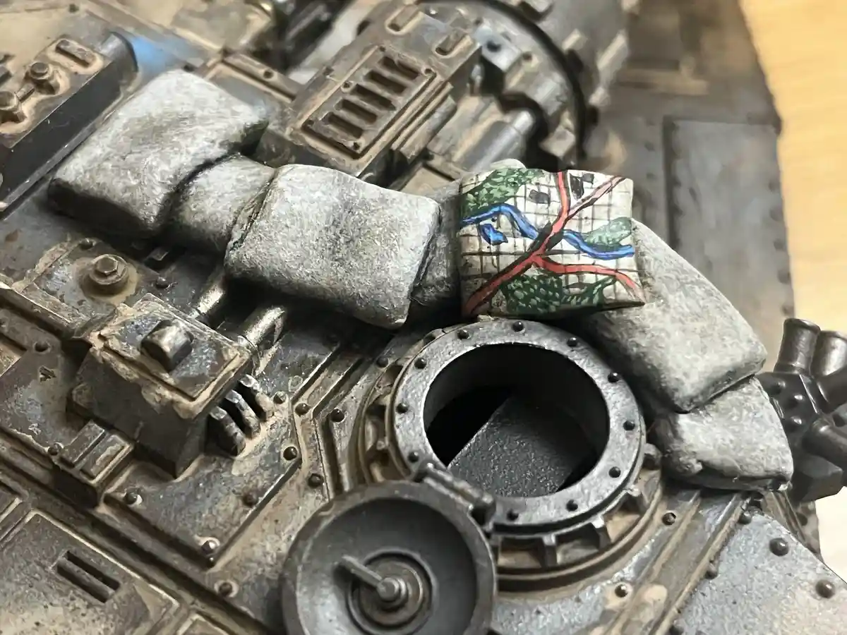 A close-up of a heavily weathered and detailed miniature war machine, likely from Warhammer 40k, with a small, hand-painted…