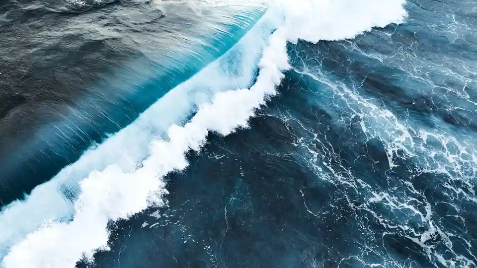 A massive wave on the open ocean exhibits a circular motion, struggling to gain forward momentum. When it hits a reef or…