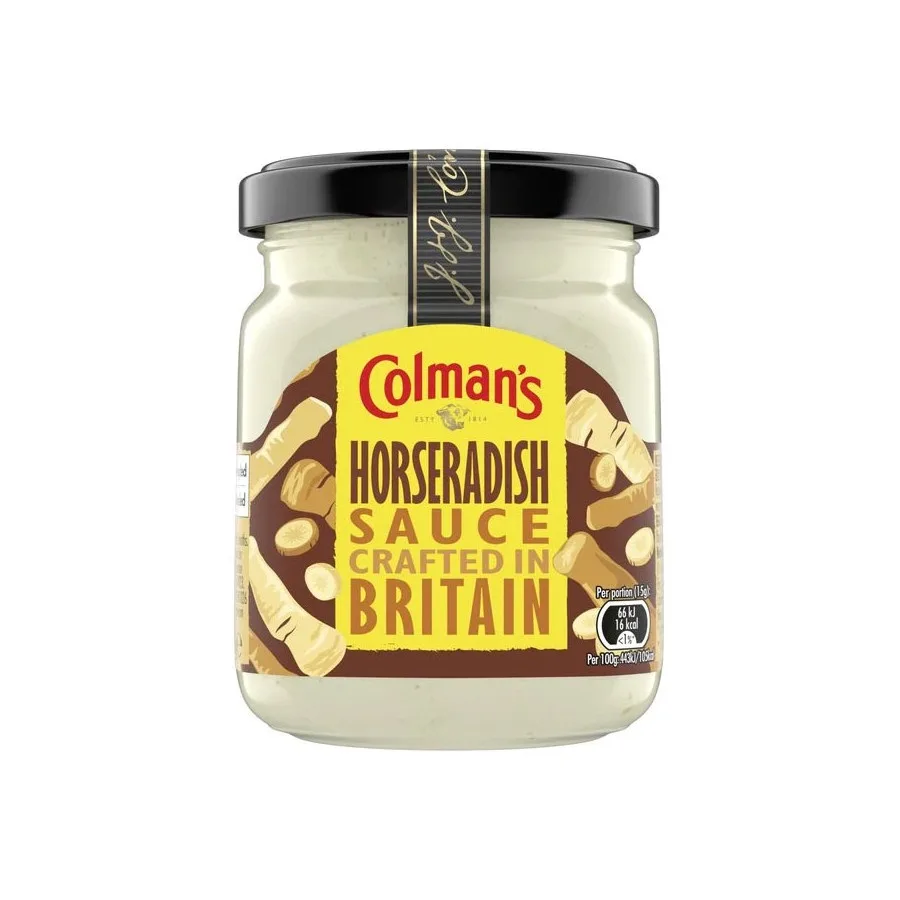 A clear glass jar of Colman's Horseradish Sauce with a black lid and a yellow and brown label featuring illustrations of…