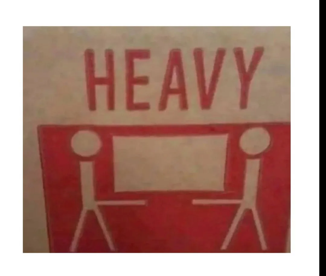 A close-up of a red warning sticker showing two stick figures lifting a heavy object, with the word 'HEAVY' printed in large…