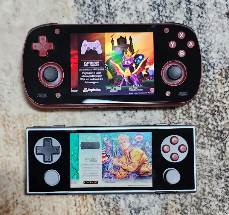 Two handheld gaming devices are shown side-by-side on a speckled countertop. The top device, a red and black handheld…