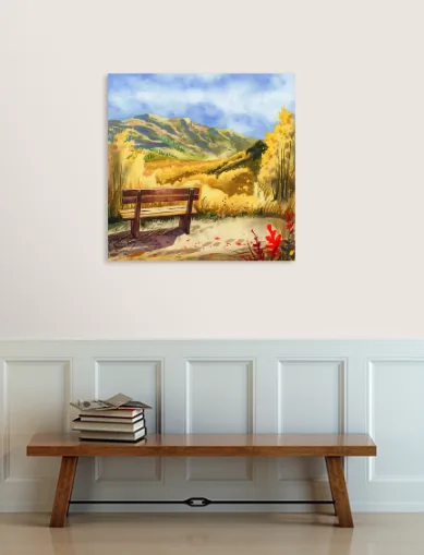 A wooden bench sits in a room beneath a framed painting of a scenic mountain landscape with autumn foliage. On top of the…