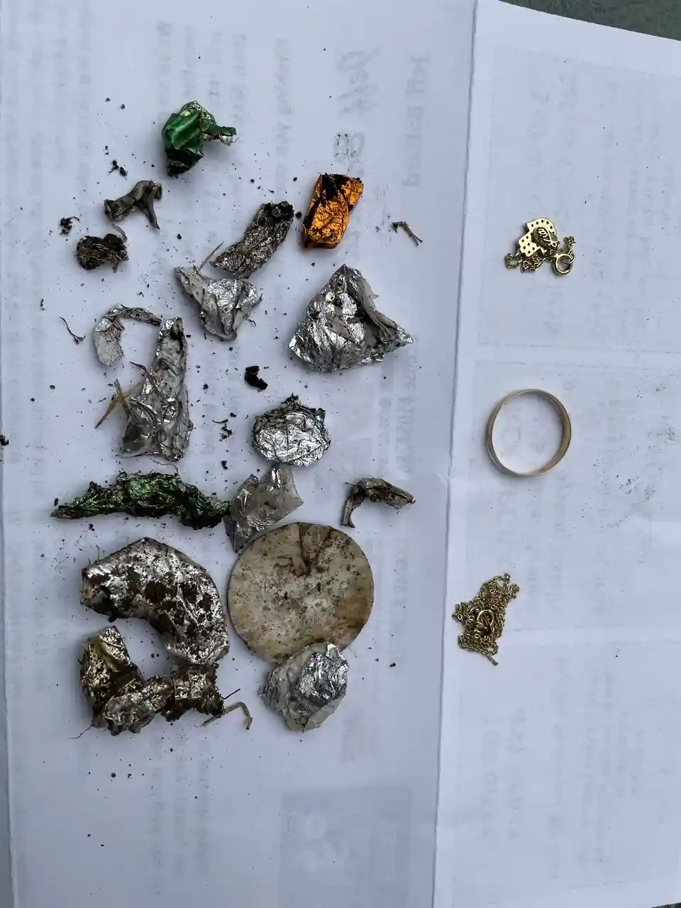 A top-down photo shows a white paper with various crumpled, dirty pieces of foil in silver, gold, and green, alongside a…