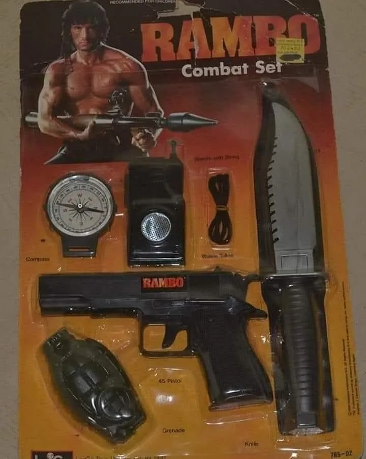 A vintage toy package labeled 'RAMBO Combat Set' features a muscular man holding a rocket launcher. Inside the blister pack…