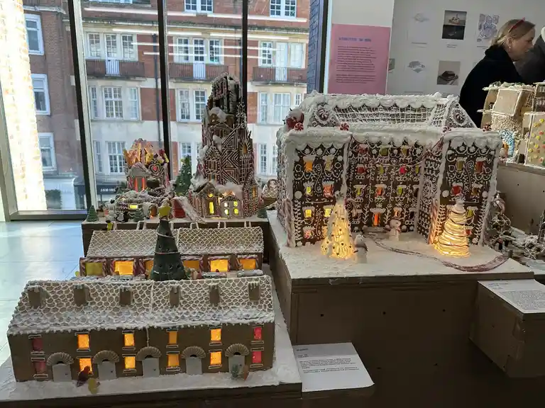 A detailed display of intricately decorated gingerbread houses with white icing, candy decorations, and glowing windows…