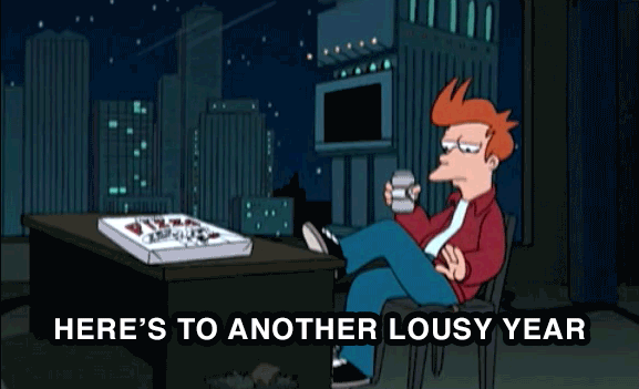 A cartoon man with spiky red hair sits in a chair at night, holding a mug, with a pizza box on a desk in front of him…
