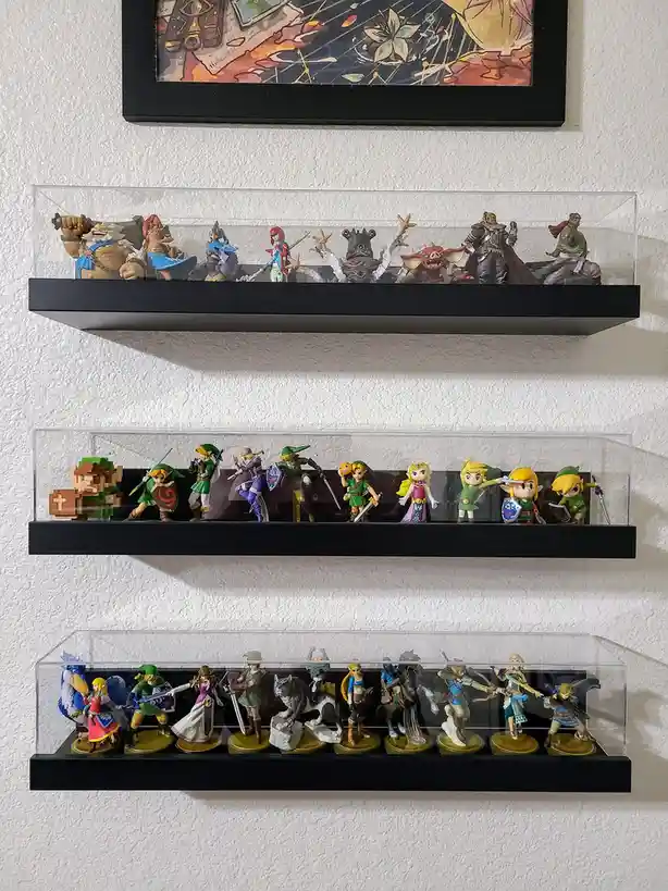 Three shelves display rows of The Legend of Zelda video game figurines in clear acrylic cases, with the top shelf showing…