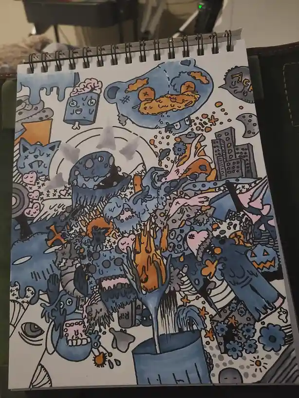 A colorful, chaotic hand-drawn illustration in a spiral-bound sketchbook shows a surreal, crowded scene with blue cartoon…