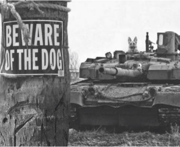 A black-and-white photo shows a 'BEWARE OF THE DOG' sign taped to a wooden post, with a military tank in the background. A…