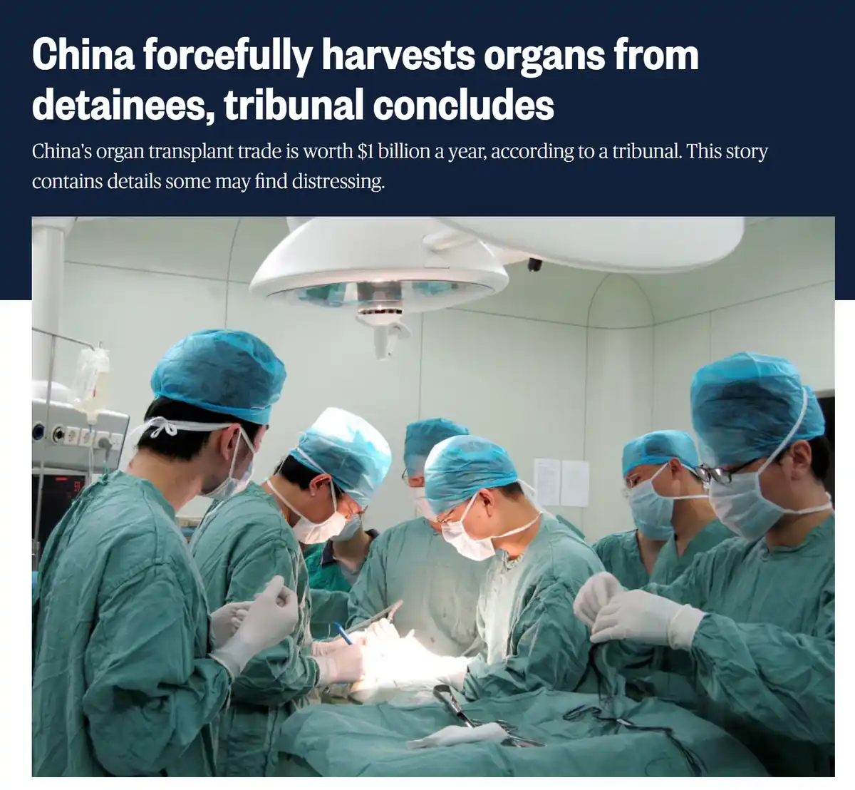 The image shows a group of surgeons in green scrubs and blue surgical caps and masks performing an operation under a bright…