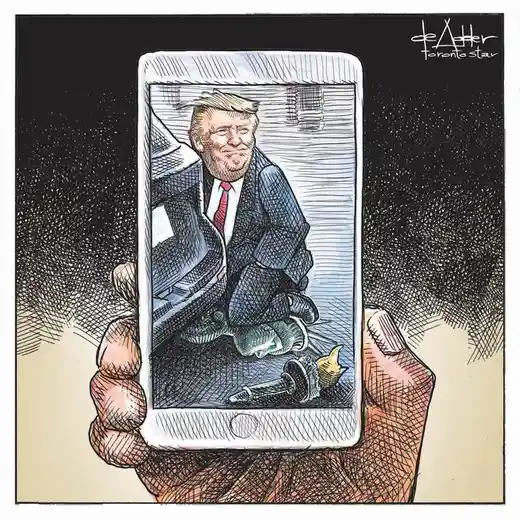 A hand holds a smartphone displaying a cartoon caricature of Donald Trump sitting on the ground with a broken flashlight…