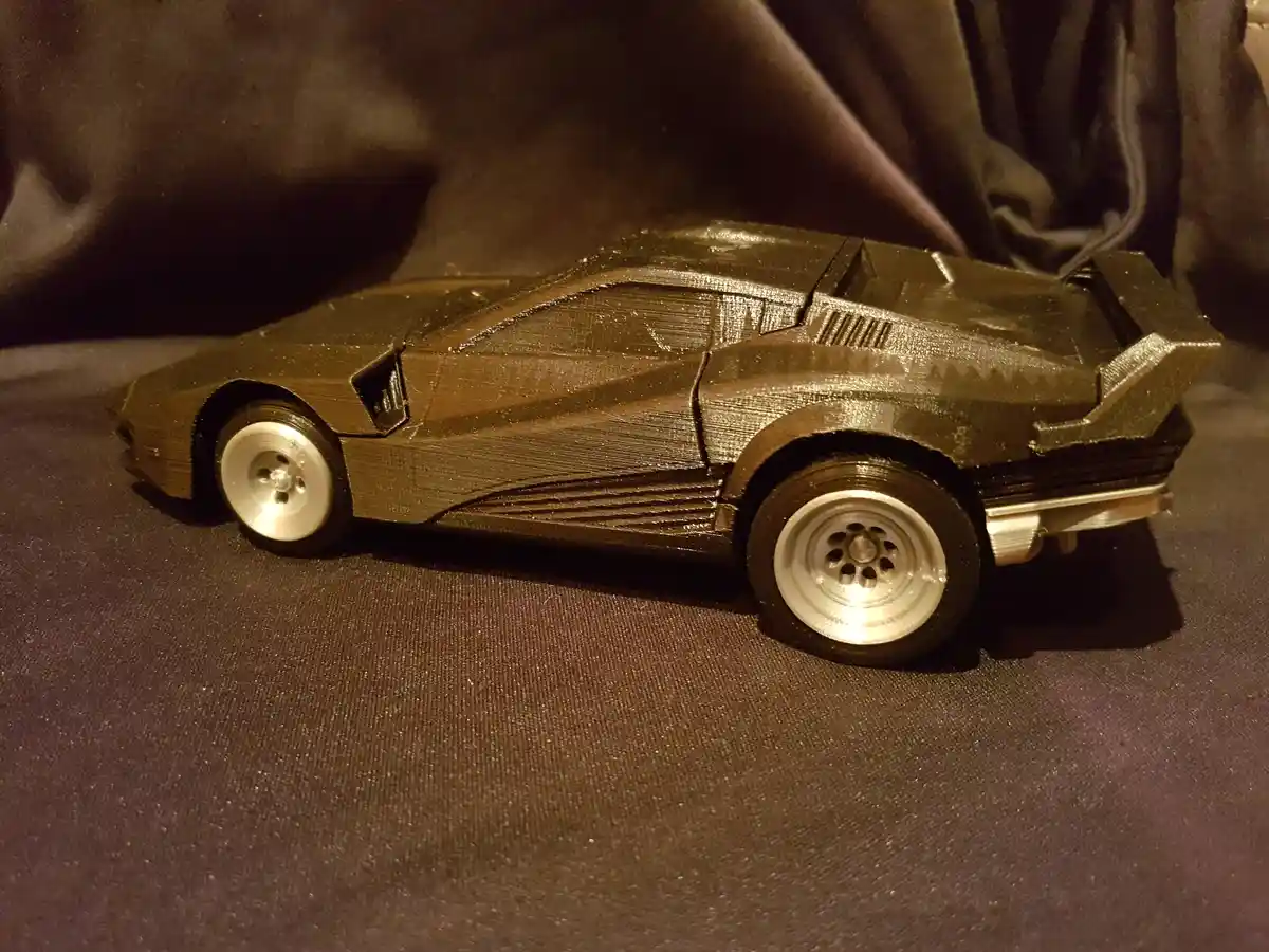 a 3d printed model of the iconic de lorean time machine from back to the future, shown in profile on a dark fabric surface…