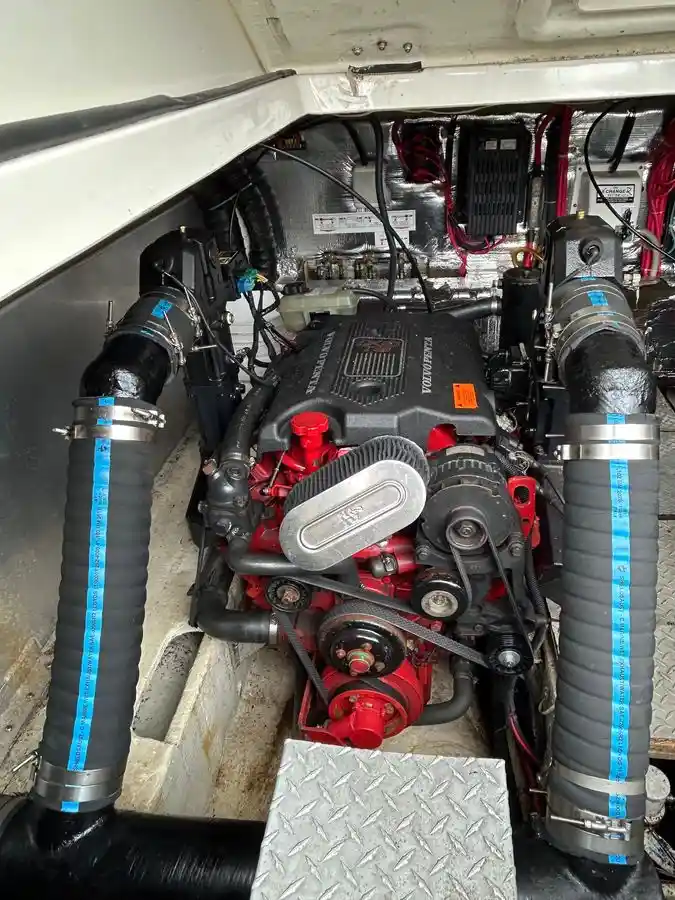 a close-up photo of a red and black yamaha outboard motor engine installed in a boat, surrounded by hoses, wires, and metal…