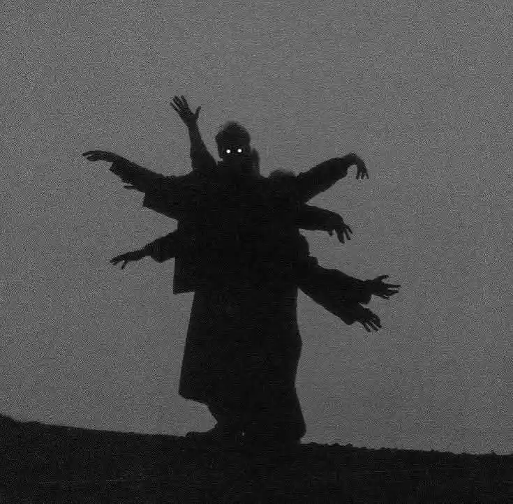A grainy, black-and-white image shows a silhouetted figure standing on a hill with multiple arms extended outward, glowing…