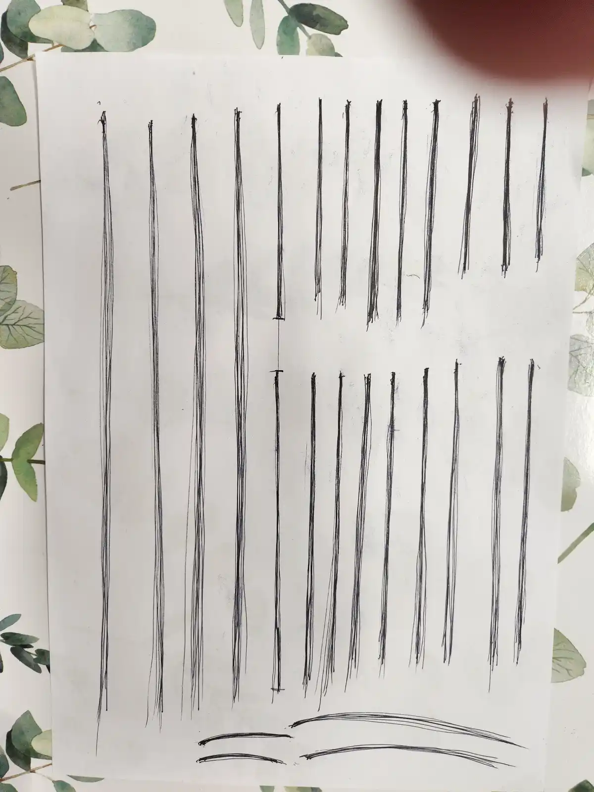 A white sheet of paper displays numerous messy, wobbly black lines drawn vertically, with a few curved lines at the bottom…