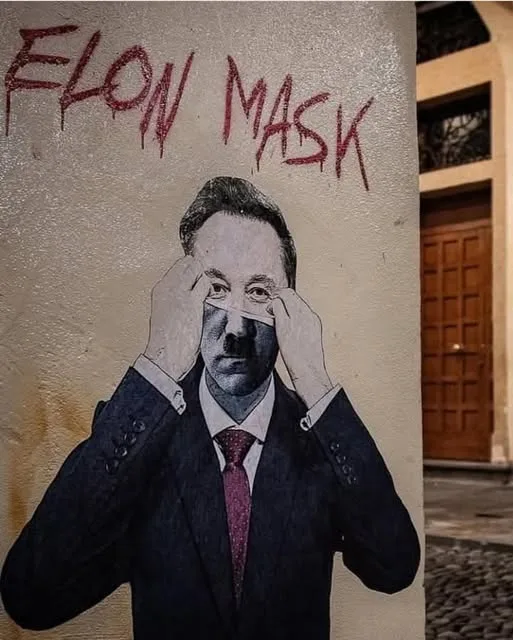 A street mural depicts a man in a suit and tie with a white tape strip across his eyes, hands pulling the tape. Above the…