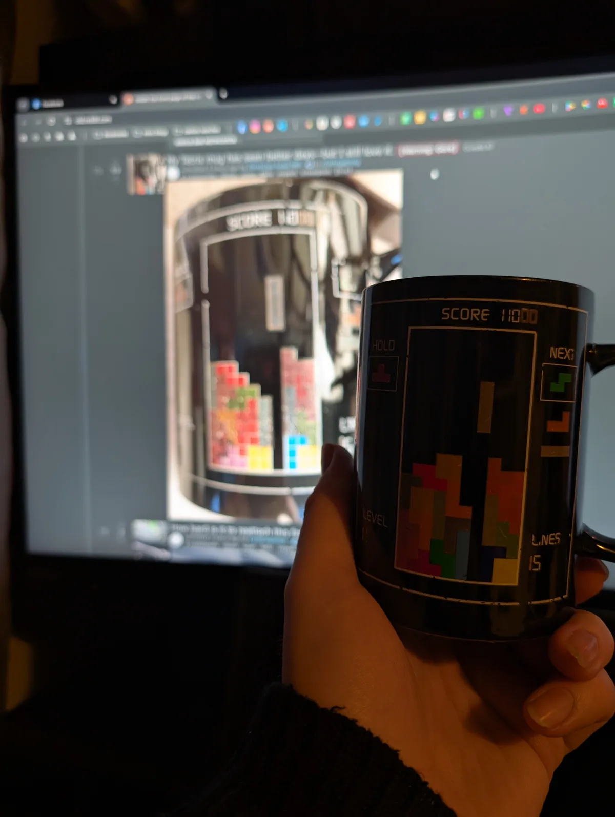 A hand holds a black mug designed to look like a classic Tetris game screen, showing a score of 11000, level 1, and 15 lines…
